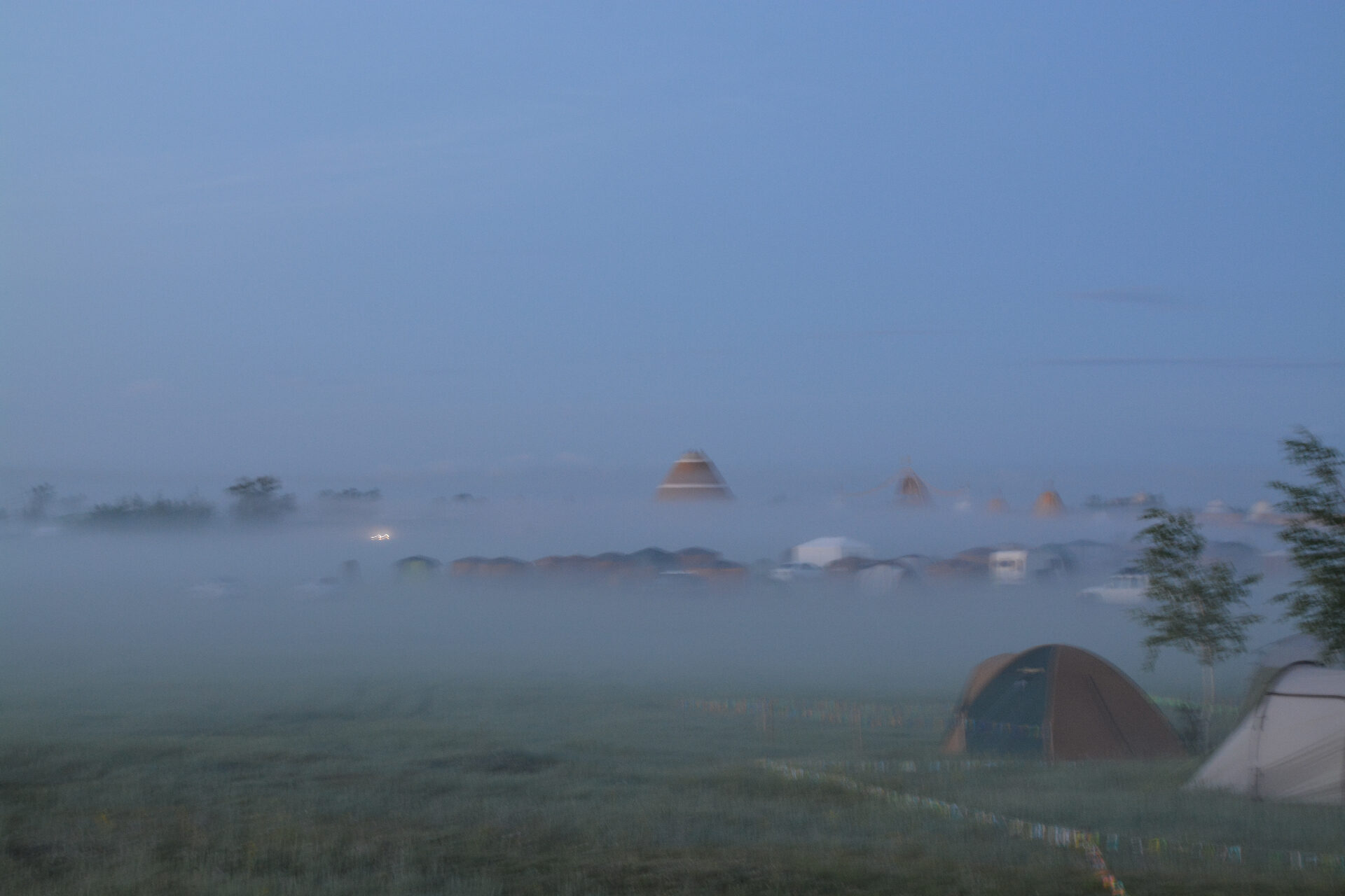Encampment of dwellings at dawn, shrouded in mist