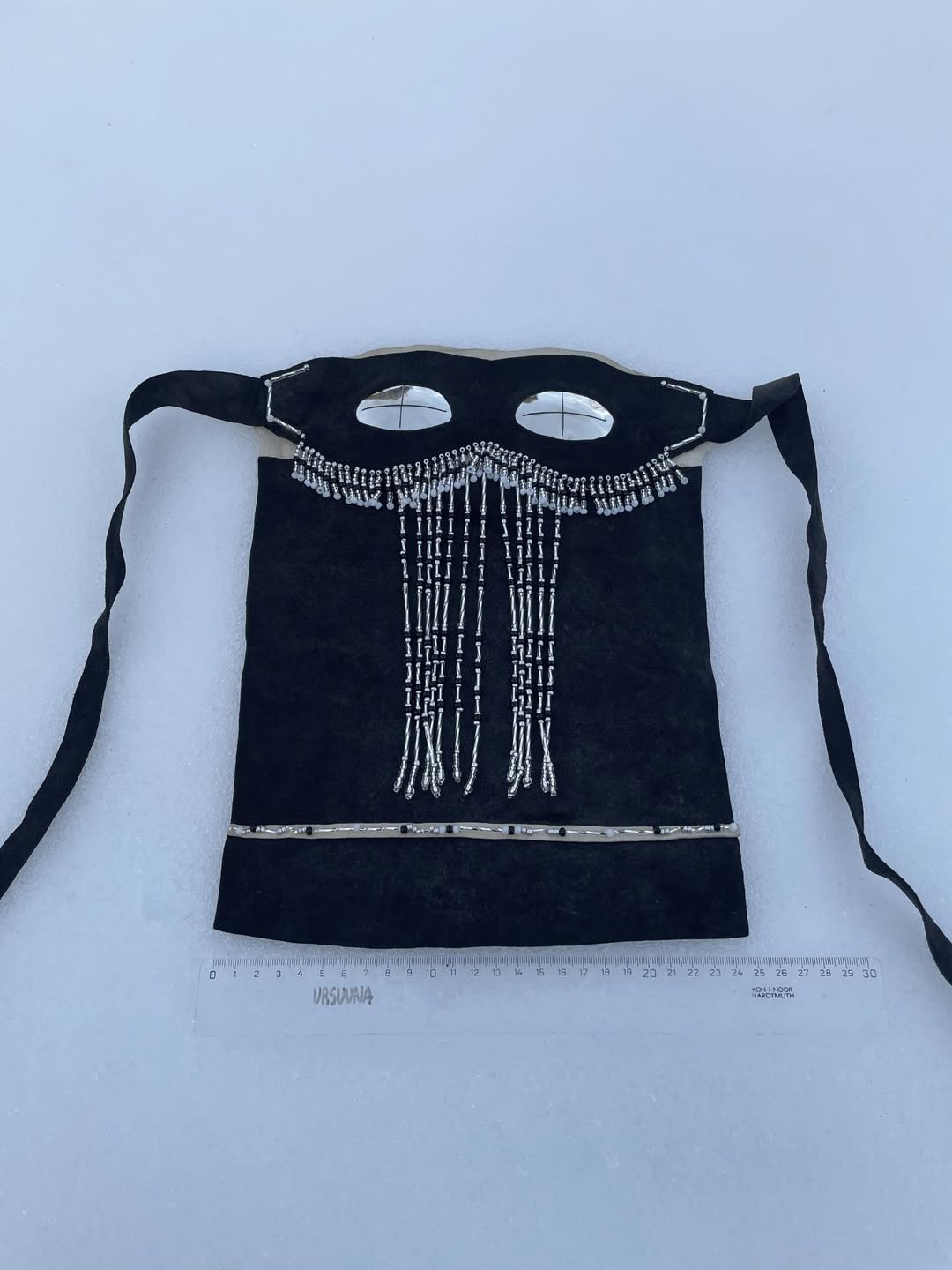 Full face silver snow goggles laid flat on snow with ruler and URSUUNA mark